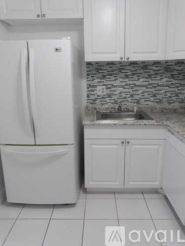 A white refrigerator in a kitchen with a stone backsplash.