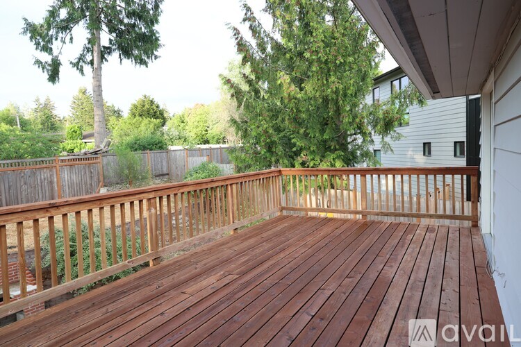 A wooden deck with a railing and trees in the background.