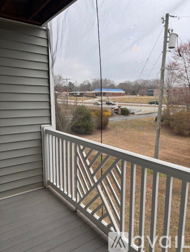 A view from a balcony looking out at a field and a building.