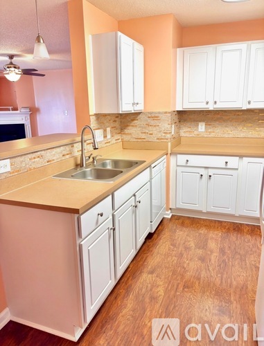 A kitchen with white cabinets and a wooden floor.
