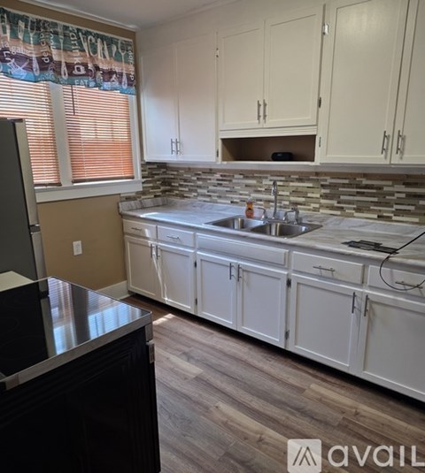 A kitchen with white cabinets and a black counter.