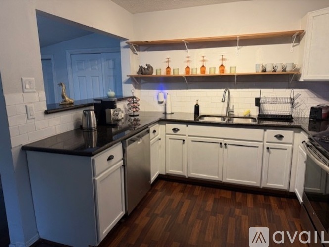 A kitchen with white cabinets and a black countertop.