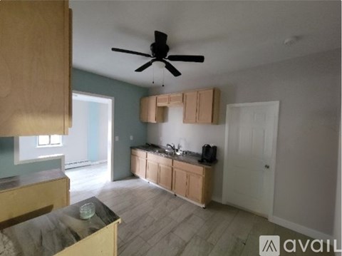 A kitchen with a ceiling fan and wooden cabinets.