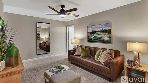 A living room with a brown couch, a coffee table, and a painting of a golf course on the wall.