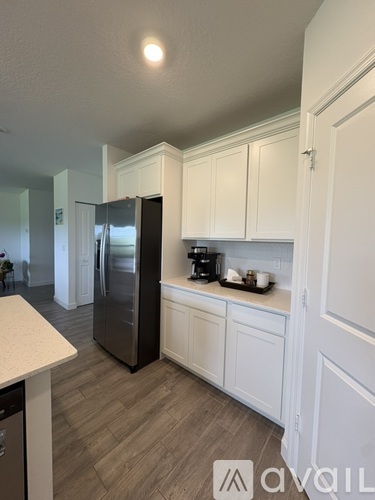 A kitchen with white cabinets and a black fridge.