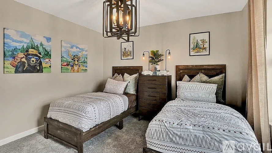 A bedroom with two beds, a chandelier, and pictures on the wall.