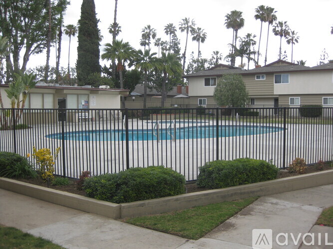 A pool surrounded by a black fence and green bushes.