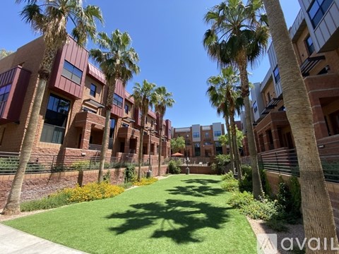A row of red brick buildings with palm trees in front.