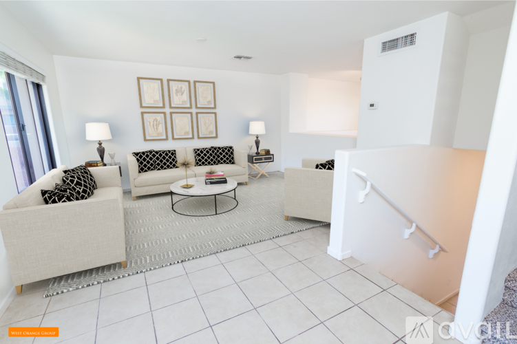 A living room with a white couch, a coffee table, and a lamp.