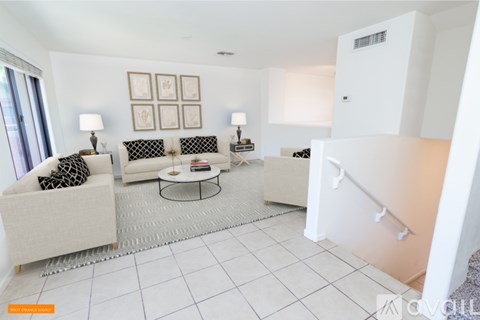 A living room with a white couch, a coffee table, and a lamp.
