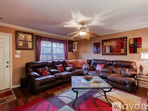 A living room with a brown leather couch and a glass coffee table.