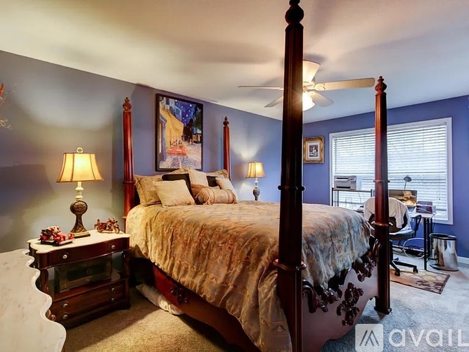 A bedroom with a four poster bed and a ceiling fan.