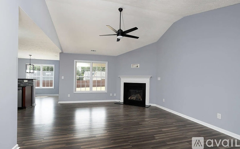 A spacious living room with a fireplace and a ceiling fan.