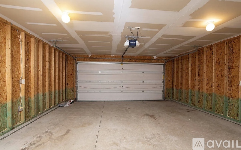 A spacious garage with a white roller shutter door and wooden walls.