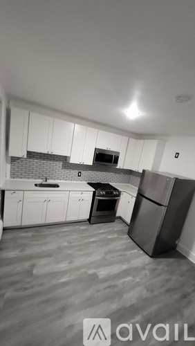 A kitchen with white cabinets and a black fridge.