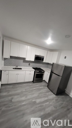 A kitchen with white cabinets and a black fridge.