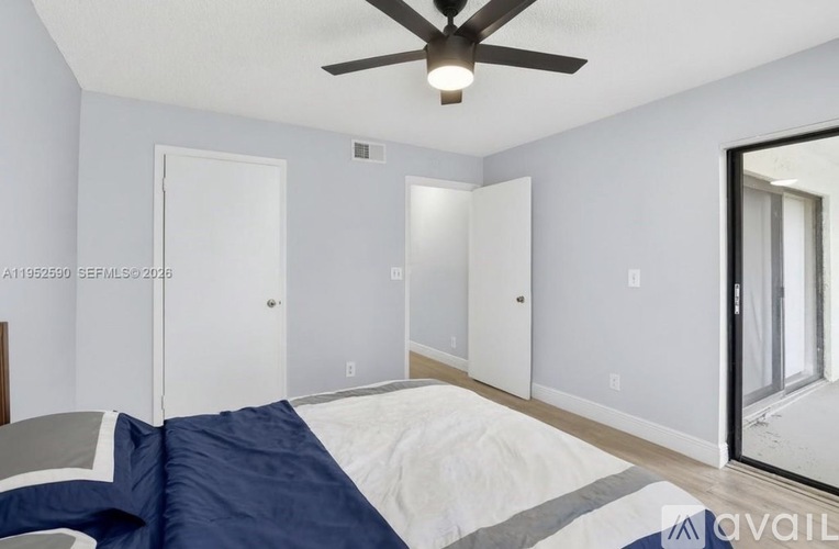 A bedroom with a bed, ceiling fan, and mirror.