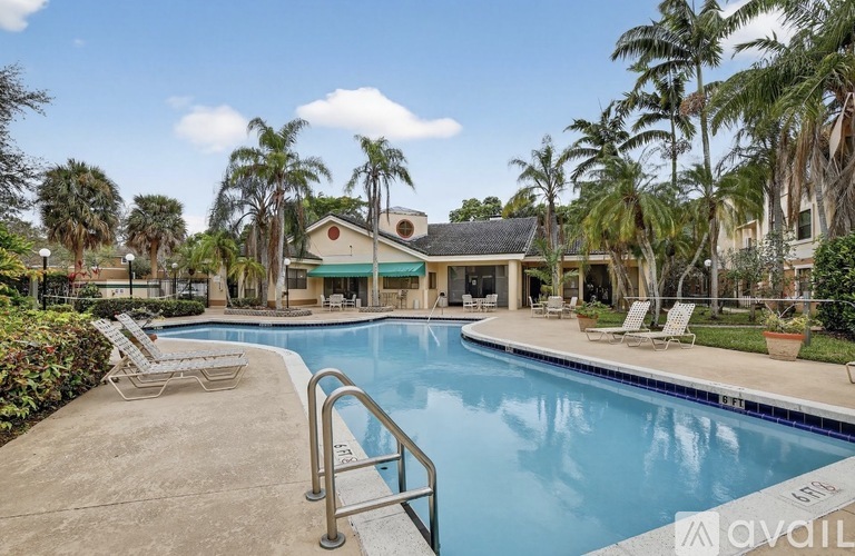 A pool surrounded by palm trees and lounge chairs.