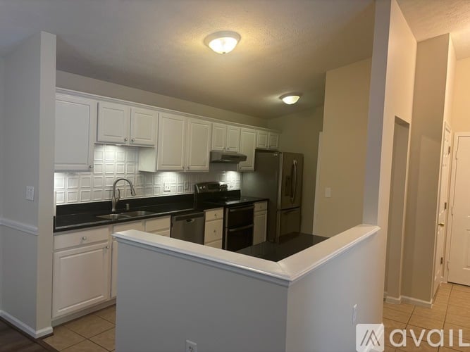 A kitchen with white cabinets and black countertops.