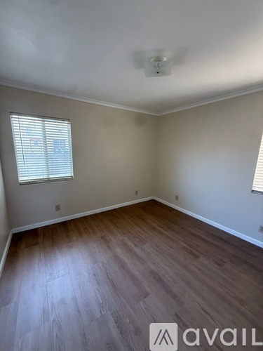A room with wooden flooring and a window with blinds.