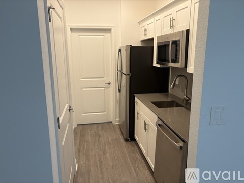 A kitchen with a black refrigerator and white cabinets.
