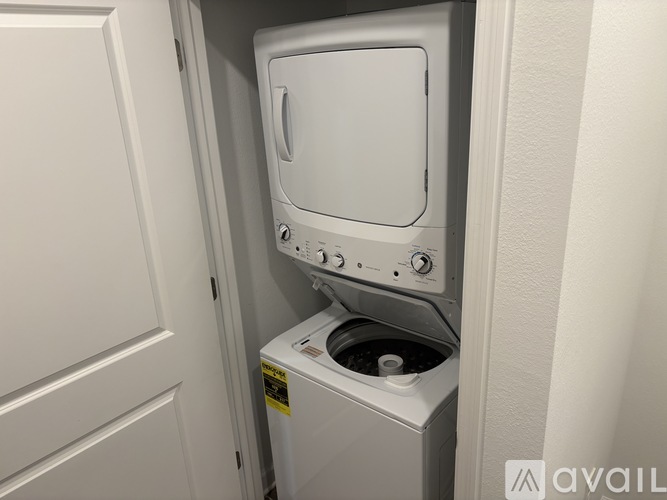 A white washing machine is placed in a small space between a door and a wall.
