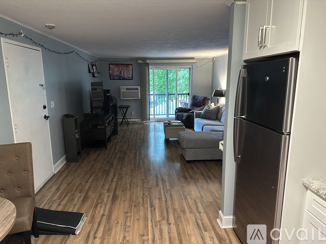 A kitchen with a refrigerator, a dining table with chairs, and a living room with a couch.