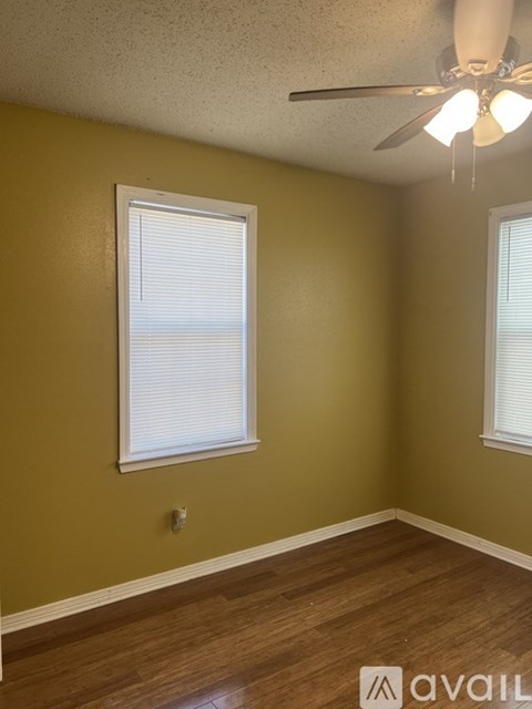 A room with a ceiling fan and two windows.
