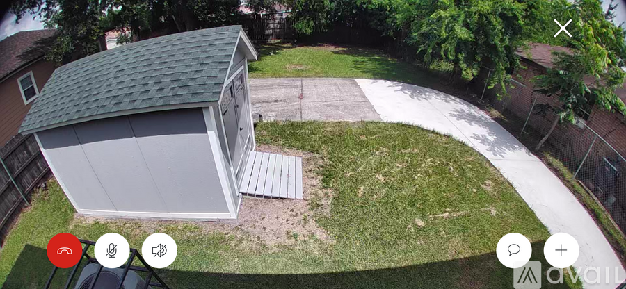 A shed with a grey roof is situated in a grassy area.