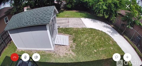 A shed with a grey roof is situated in a grassy area.