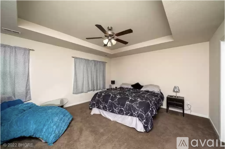 A bedroom with a bed, a ceiling fan, and a nightstand.
