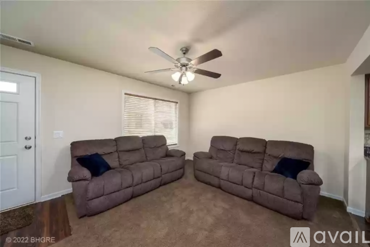 A living room with two brown couches and a ceiling fan.