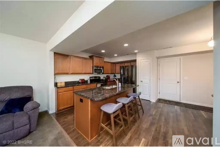 A kitchen with wooden cabinets and a central island with stools.