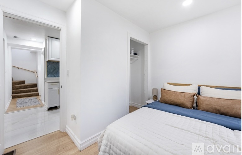 A bedroom with a large bed and a staircase in the background.