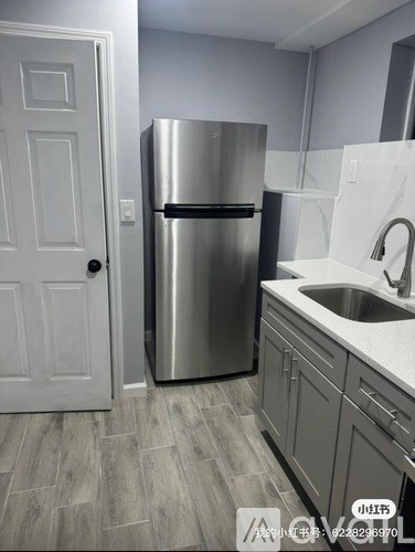 A kitchen with a stainless steel refrigerator and a white door.