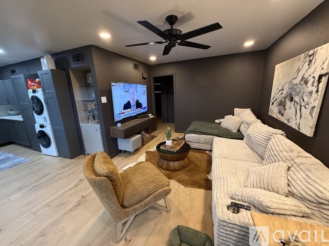 A living room with a brown chair, a white couch, and a ceiling fan.