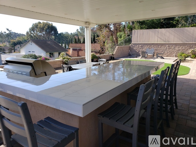 A white outdoor kitchen with a glass table and chairs.