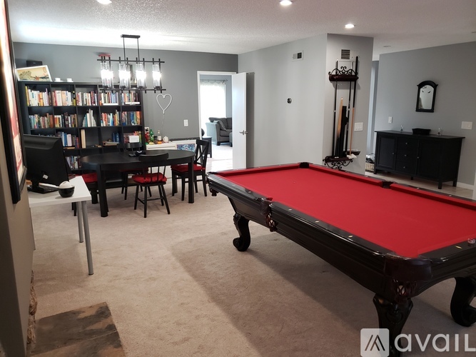 A room with a pool table, a dining table, and a bookshelf.