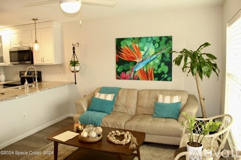 A living room with a couch, a coffee table, and a painting on the wall.