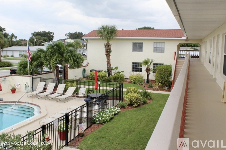 A pool and patio area with a black fence and red umbrellas.