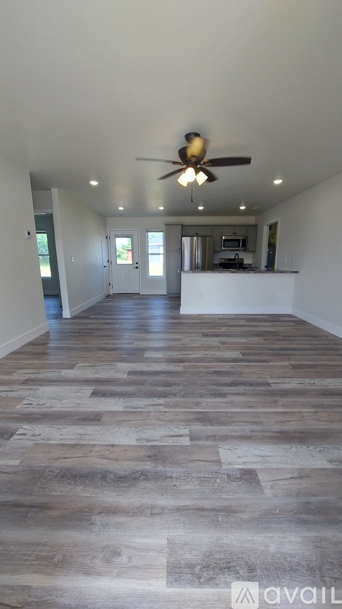 A spacious room with a ceiling fan and wooden flooring.