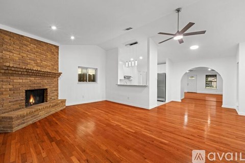 A spacious room with a fireplace and wood flooring.