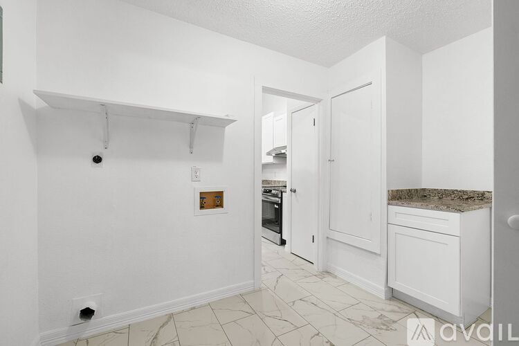A kitchen with white cabinets and a marble countertop.