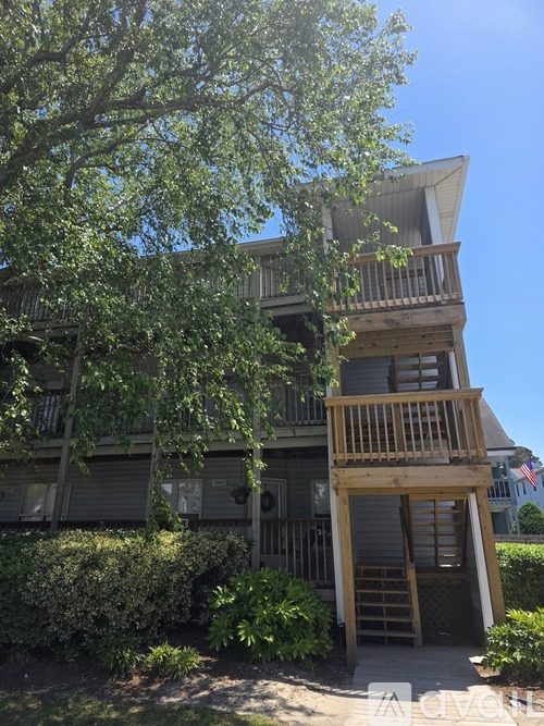 A tree is in front of a grey building.