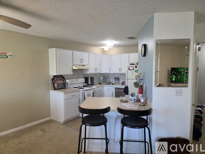 A kitchen with white appliances and a table with two chairs.