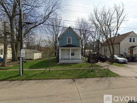 A blue house with a white fence is in front of a tree and a sign that says 25.