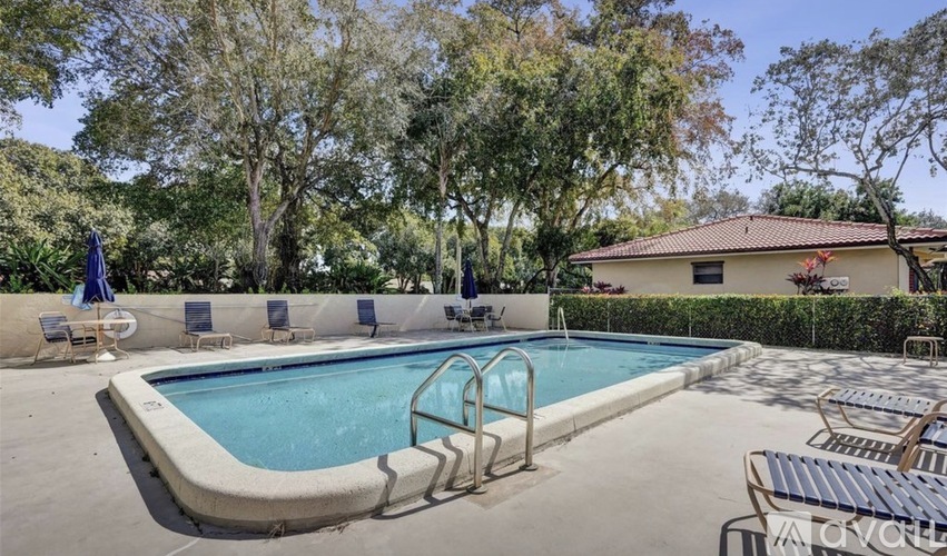 A pool surrounded by trees and chairs.