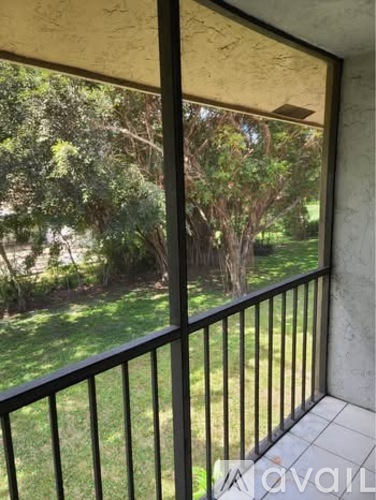 A balcony with a black railing and a view of a green lawn and trees.