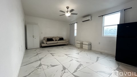 A living room with a couch, a ceiling fan, and a window.