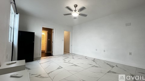 A spacious room with a marble floor and a ceiling fan.